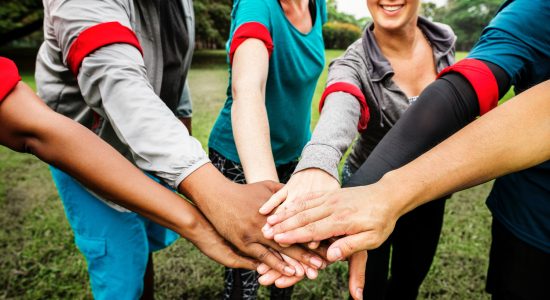 personnes formant une équipe avec des brassards rouges joignant les mains