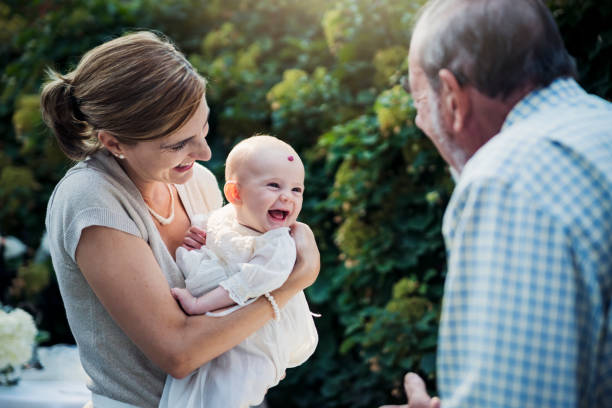 Jeune maman qui tient son enfant dans ses bras pendant son baptême