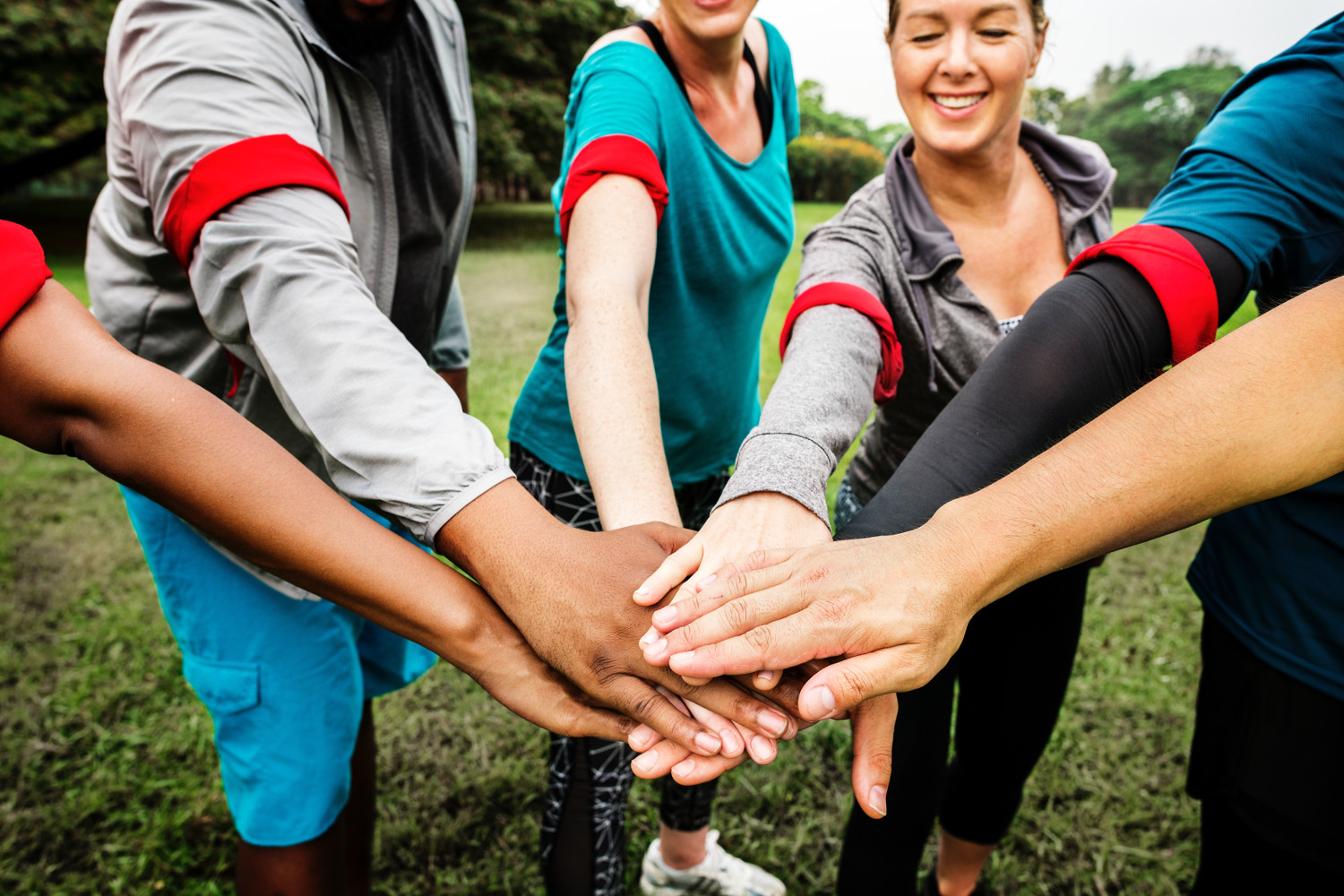 personnes formant une équipe avec des brassards rouges joignant les mains